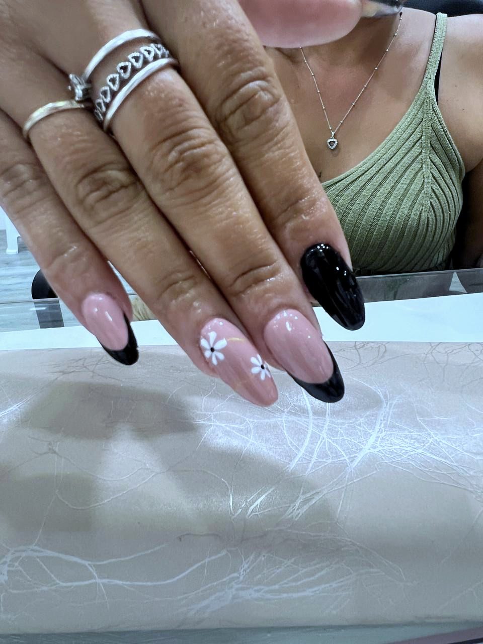 Uñas almendra con francesa negra y nail art de margaritas blancas.